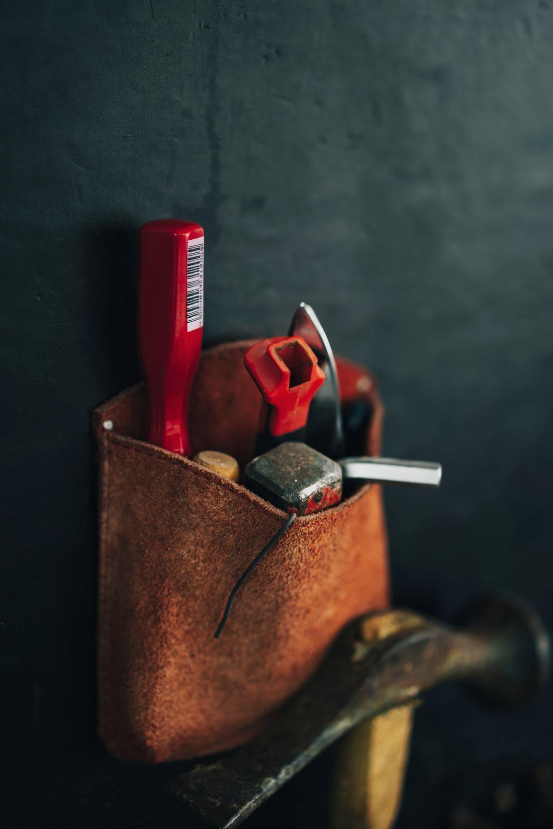 Leather tool pouch hanging on a dark wall